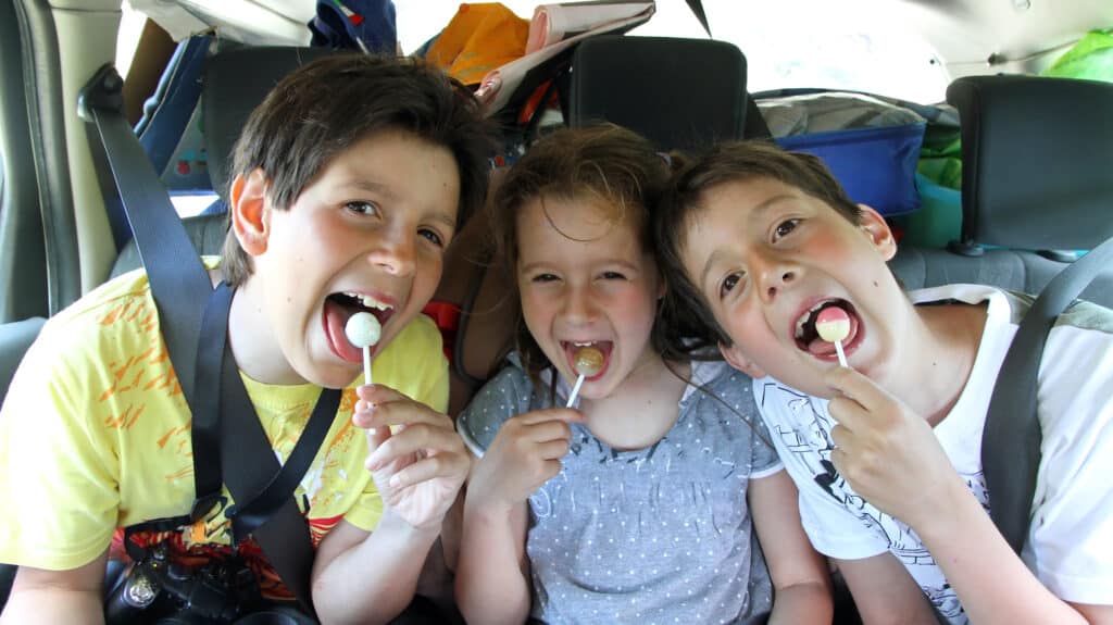 bilferie 3 børn på bagsædet i bilen med hver deres slikkepind