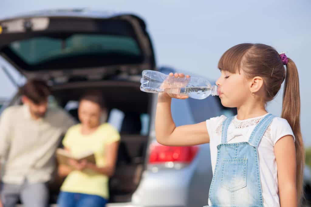 familie på bilferie pige drikker vand mens de holder pause